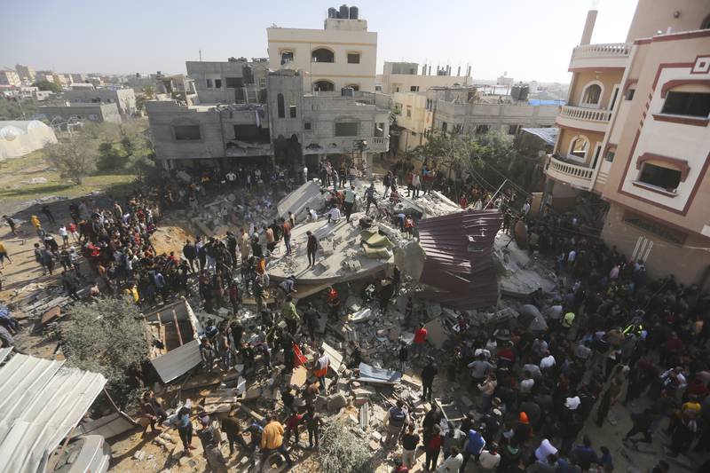 Palestinians look for survivors after an Israeli strike on the Gaza Strip in Rafah on Saturday,...