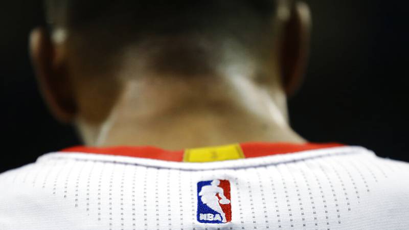 FILE - In this April 7, 2015 file photo, an NBA logo is displayed on the back of a player's...